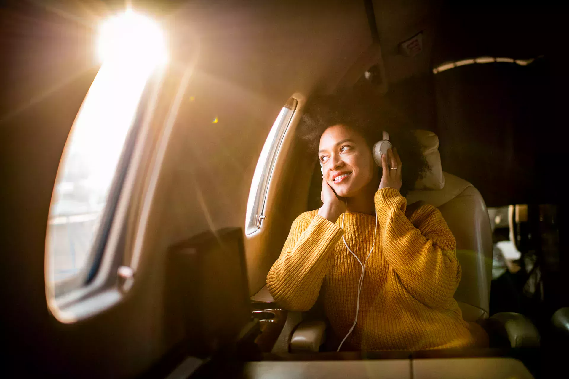 Mujer sentada en un avión escuchando música con auriculares